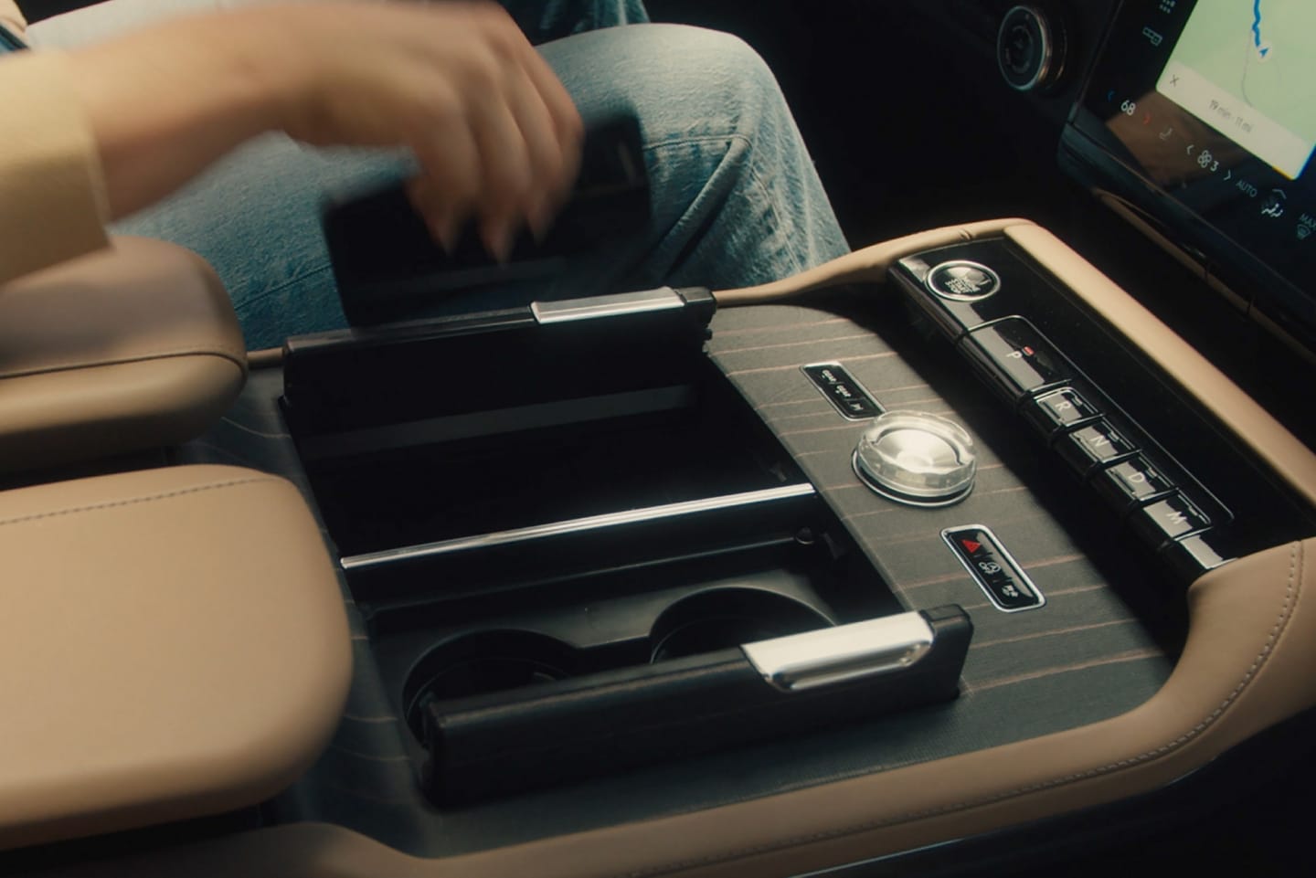 The driver of a 2025 Lincoln Navigator® SUV reaches to place a smartphone on the wireless charging pad